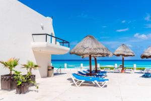 een strand met stoelen en parasols en de oceaan bij Lindo loft en playa Marlin, 2 min de Plaza la Isla - Mar310 - in Cancun