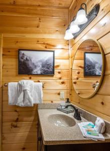 a bathroom with a sink and a mirror in a log cabin at New Listing! Indoor Private Heated Pool, Less than 2 miles from Dollywood, Walk to Parkway, 4 Ensuite Bedrooms Sleeps 14, Dog Friendly, Game Room with TV, Arcade and Foosball, Hot Tub, BBQ, Smart TV and Wifi, Fully Loaded Kitchen, Washer and Dryer in Pigeon Forge