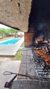 a grill with food cooking on it next to a pool at Cabaña LA JUANA in Villa Anizacate
