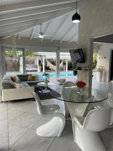 uma sala de estar com uma mesa de vidro e cadeiras brancas em Villa Almeida à 500m de la plage em Courcelles