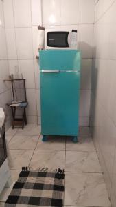 a blue refrigerator with a microwave on top of it at Casa e camping Reinaldo e Julia recanto das árvores in Itamonte