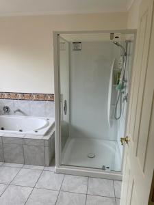 a bathroom with a shower and a tub and a sink at Spacious Home in Paraparaumu