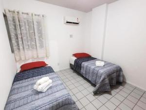1 dormitorio con 2 camas y ventana en Porto da praia na Jatiuca, en Maceió