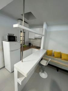 a white kitchen with a bench and a chair in it at Casa marea in Puerto Calero