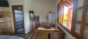 a room with a kitchen with a table and a refrigerator at Pousada Colina das Maritacas in São Thomé das Letras