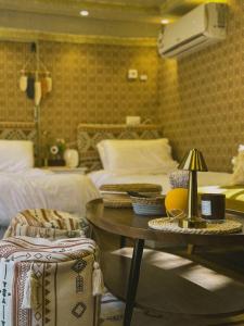 a bedroom with two beds and a table with a lamp at Four caravan in AlUla