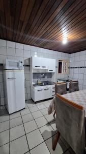 una cocina con electrodomésticos blancos y una mesa. en Casa com quintal próxima de Torres, en Passo de Torres