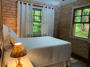 1 Schlafzimmer mit einem weißen Bett und 2 Fenstern in der Unterkunft Casa ecológica na Montanha in Praia Grande