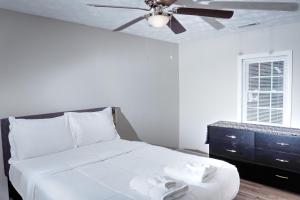 a bedroom with a white bed with a ceiling fan at Brick Beauty Fayetteville 3 bedroom Mins from Downtown in Fayetteville