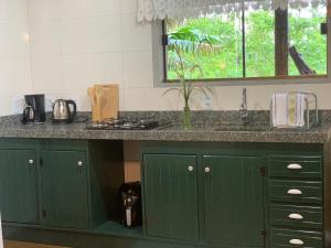 eine Küche mit grünen Schränken und einer Theke mit Fenster in der Unterkunft Casa ecológica na Montanha in Praia Grande + 13 Fotos