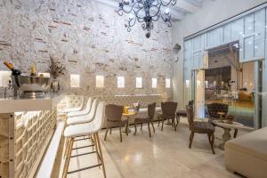 a dining room with white chairs and a stone wall at Hotel Casa del Gobernador in Cartagena de Indias