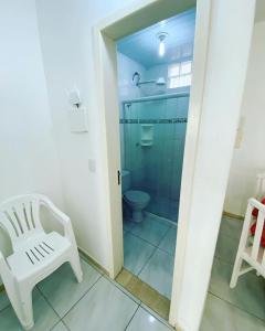 a bathroom with a glass shower and a white chair at Pousada Ilha dos Corais in Palhoça