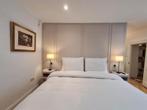Pembroke Guest Suite في دبلن: سرير أبيض كبير في غرفة بها مصباحين