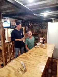 dos hombres parados en una cocina con una mesa de madera en Hostal Ñuca Huasi, en Tambillo