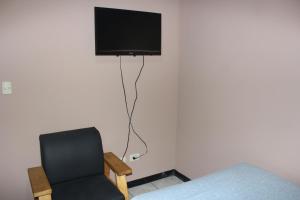 a room with a chair and a television on a wall at Hotel El Dorado in San José