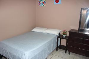 um pequeno quarto com uma cama e uma cómoda em Hotel Dorado em San José