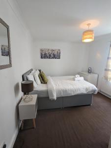 a white bedroom with a bed and a lamp at Welcoming Flat By Kasar Stays in Gillingham