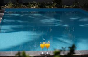two glasses of orange juice sitting next to a swimming pool at Villa Windfall Unawatuna in Unawatuna