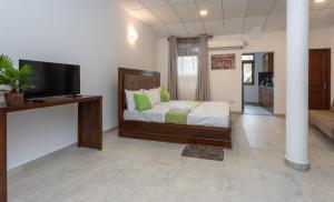 een slaapkamer met een bed en een flatscreen-tv bij Villa Windfall Unawatuna in Unawatuna