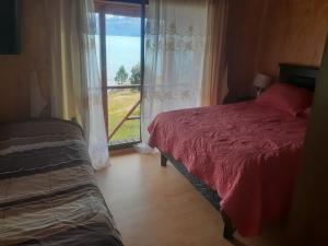 ein Schlafzimmer mit einem Bett und einem großen Fenster in der Unterkunft La Lomita Guadal in Puerto Guadal