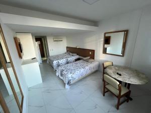 1 dormitorio con 2 camas, mesa y silla en VICTÓRIA MARINA FLAT - vista avenida, en Salvador