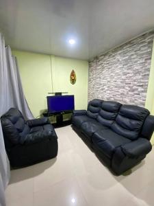 uma sala de estar com um sofá de couro e uma televisão em Departamento en la Fortuna em La Fortuna