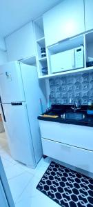 a white kitchen with a sink and a refrigerator at VICTÓRIA MARINA FLAT - vista avenida in Salvador