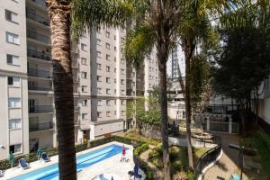 een appartementencomplex met een zwembad en palmbomen bij Just Vero Apartament - GRU in Guarulhos