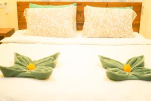 2 almohadas en una cama con almohadas verdes y blancas en I Gusti Nyoman Oka Homestay, en Ubud