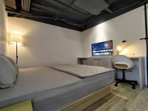 sypialnia z łóżkiem, biurkiem i monitorem w obiekcie 肆樓寓所 w mieście Tainan