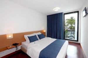 sypialnia z dużym łóżkiem i dużym oknem w obiekcie Thomas Place w mieście Ponta Delgada