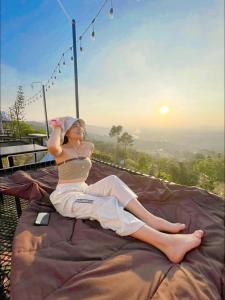 a woman sitting on a blanket on a bed at Peace Zone เขาค้อ in Khao Kho