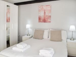 a white bedroom with a white bed with two lamps at Beck Cottage in Millom