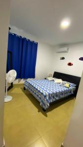 1 dormitorio con cama y cortina azul en Relajate en un hermoso apartamento Duplex cerca de la playa y piscina en Playa Blanca, Farallon, en Río Hato