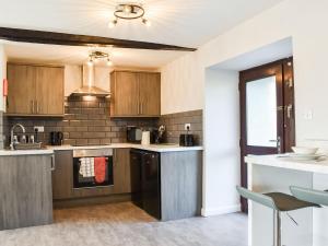 a kitchen with wooden cabinets and a sink at Beck Cottage in Millom