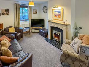 a living room with a fireplace and a television at Apple Tree Cottage in Threlkeld