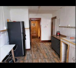 een keuken met een zwarte koelkast en een houten vloer bij Alojamiento Punta Arenas in Punta Arenas