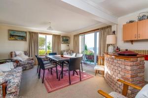 een woonkamer met een tafel en een open haard bij Stunning 180 degree River Derwent and Hobart View! in Sandy Bay
