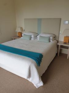 1 dormitorio con 1 cama blanca grande con almohadas azules en The Retreat - Luxury Hillside villa at Te Ngaere Bay en Kaeo