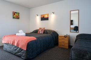 1 dormitorio con 2 camas y espejo en Fitzherbert Court Motel, en Hokitika