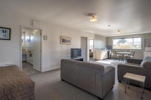 a living room with a couch and a bed and a kitchen at Fitzherbert Court Motel in Hokitika