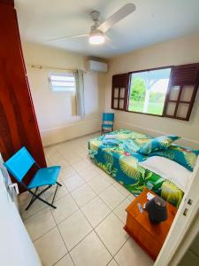 1 dormitorio con 1 cama, 2 sillas y mesa en Villa Créole vue sur mer des Caraïbes, en Le Carbet