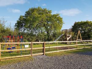 een houten hek met een speeltuin in een park bij Acacia in Thornbury