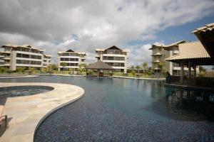 a swimming pool in front of some apartment buildings at Beach Place Resort - Térreo in Aquiraz