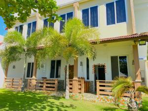 a house with palm trees in front of it at Oceanfront Beach Resort in Siquijor