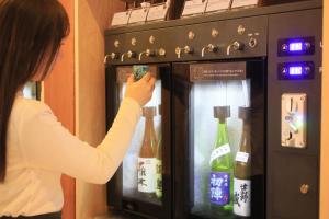 une femme met une bouteille dans un réfrigérateur dans l'établissement Yutorelo Tsuwano, à Tsuwano