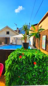 einem grünen Busch mit roten Blumen auf dem Balkon in der Unterkunft Villa 20 min de Paris avec spa, piscine chauffée et club in Gagny