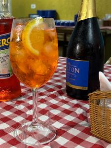 a drink in a wine glass on a table with a bottle at Villa Di Verona Charm Hotel in Guarujá