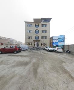 ein Gebäude mit Autos auf einem Parkplatz in der Unterkunft Hotel Nouvella Residency in Srinagar