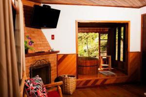 a living room with a fireplace and a television at Pousada chalés Binitz in Visconde De Maua